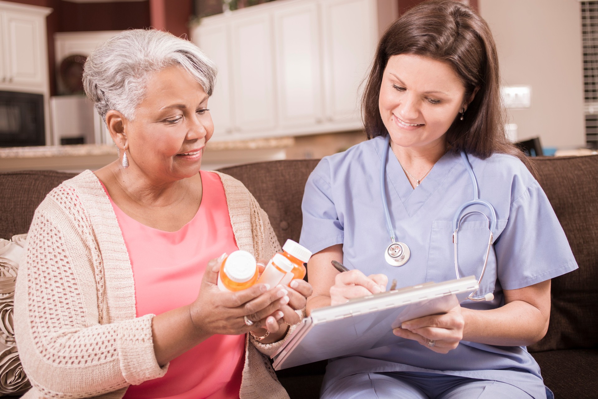 Home healthcare nurse explains medications to senior adult woman.